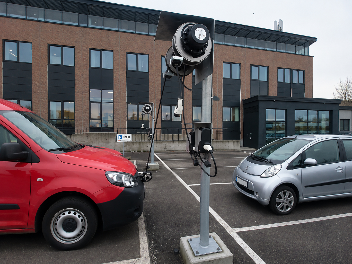 Borne de recharge et enrouleur de câble sur un parking de flotte, câble connecté à un utilitaire